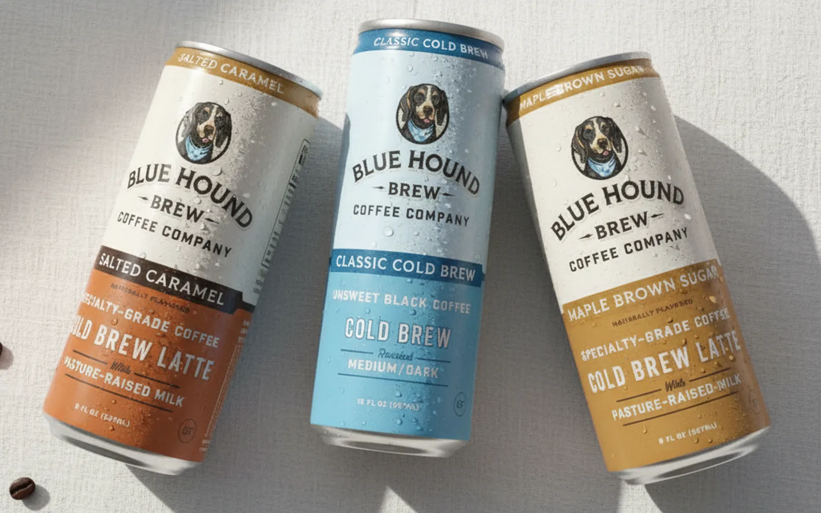 Three Blue Hound Brew cold brew cans on a linen surface with coffee beans, generated by the pipeline.